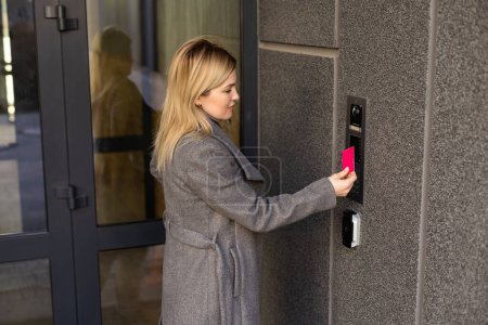 Primer plano de la mujer utilizando el intercomunicador de tarjetas en la entrada del edificio