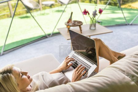 Glückliche junge Frau chattet online mit dem Laptop im Kuppelzelt. Glamping-Urlaubskonzept.