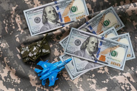Tanque de juguete en billetes de cien dólares de los EE.UU. billetes de cerca. El concepto de costos de guerra, gasto militar y crisis económica. Foto de alta calidad