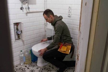 Repairman hands installing flush toilet, toilet bowl in the bathroom. High quality photo