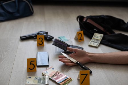 Photo for Hand of dead victim surrounded by evidence markers and objects on floor of residential apartment. Crime scene investigation and documentation process. High quality photo - Royalty Free Image