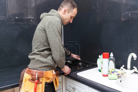 A gas engineer repairs a gas stove in the kitchen. The call of the master gas fitter to the house. . High quality photo