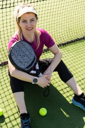 Sportliche europäische Padel-Tennisspielerin trainiert auf dem Außenplatz mit einem Schläger, um den Ball zu treffen. Hochwertiges Foto