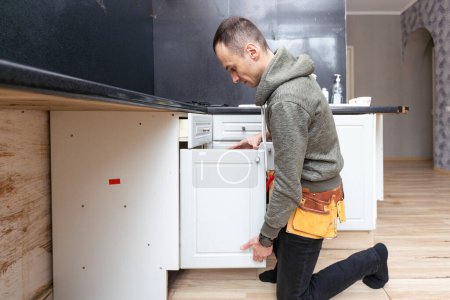 Téléchargez les photos : Un vieil homme démonte la cuisine de l'appartement hors service. Photo de haute qualité - en image libre de droit