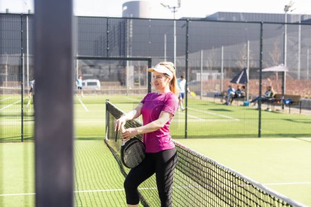 Sporty european woman padel tennis player trains on the outdoor court using a racket to hit the ball. High quality photo