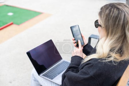 Téléchargez les photos : Femme sur le terrain de golf avec smartphone avec application de paris sportifs. Photo de haute qualité - en image libre de droit