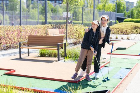 Téléchargez les photos : Mère et fille jouant au mini golf, les enfants profitant des vacances d'été. Photo de haute qualité - en image libre de droit
