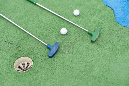 Téléchargez les photos : Clubs de mini-golf et balles de différentes couleurs posées sur gazon artificiel. Photo de haute qualité - en image libre de droit