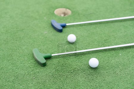 Téléchargez les photos : Clubs de mini-golf et balles de différentes couleurs posées sur gazon artificiel. Photo de haute qualité - en image libre de droit