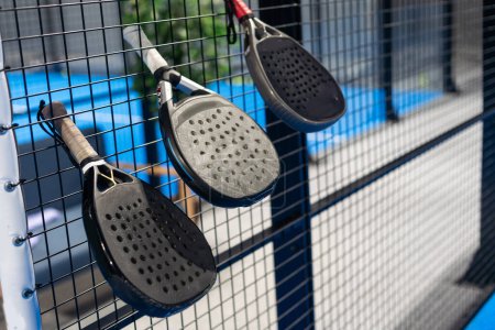 Paddle tennis: Padel racket and ball in front of an outdoor court. High quality photo