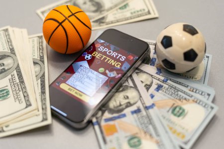 Foto de Smartphone con aplicación móvil de juegos de azar y pelota de baloncesto con el dinero de cerca. Concepto de deporte y apuestas. Foto de alta calidad - Imagen libre de derechos