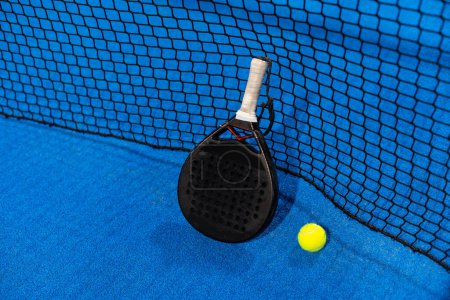 raquette de paddle tennis et balles sur le terrain de paddle bleu. Photo de haute qualité