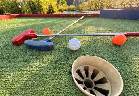 Téléchargez les photos : Putters de golf colorés avec des balles de golf sur gazon synthétique. Photo de haute qualité - en image libre de droit