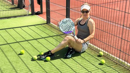 Foto de Retrato de mujer emocional activa jugando padel tenis en pista abierta en verano, balanceo raqueta para devolver la pelota sobre la red.. Foto de alta calidad - Imagen libre de derechos