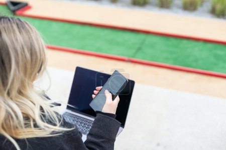 Téléchargez les photos : Femme sur le terrain de golf avec smartphone avec application de paris sportifs. Photo de haute qualité - en image libre de droit