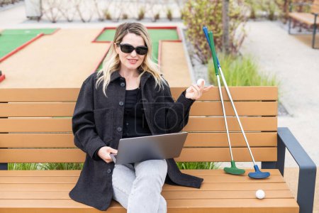 Una mujer de negocios usando un portátil en un campo de golf. Foto de alta calidad