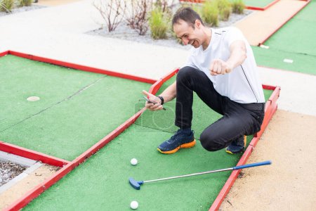 Téléchargez les photos : Joueur regarde son coup sur un terrain de mini golf. Photo de haute qualité - en image libre de droit