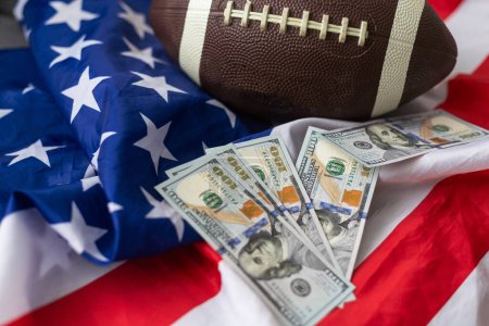 Geld und Rugbyball auf amerikanischem Flaggenhintergrund, Nahaufnahme. Konzept der Sportwette. Hochwertiges Foto