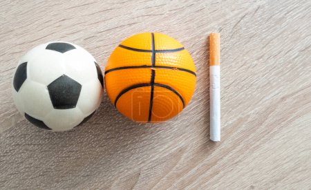 Fumar o deportes. Pelota deportiva y paquete de cigarrillos en el fondo de la mesa. Vista superior. Foto de alta calidad