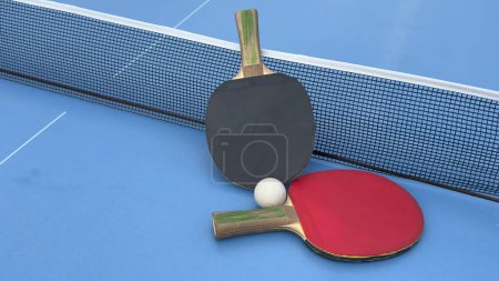 Rackets and ball on a blue tennis table - equipment for table tennis or ping pong. Old and new rackets close-up. Sports concept. . High quality photo