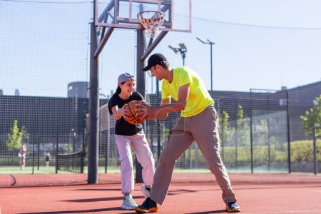 A happy father and teen daughter playing basketball outside at court. High quality photo