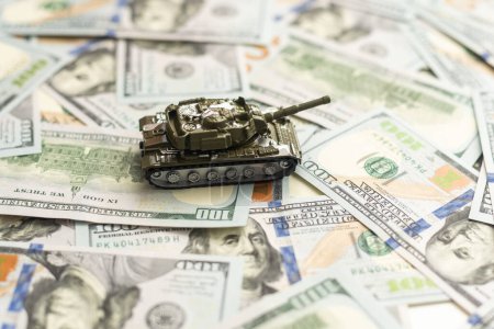 Toy tank on US hundred dollar bills banknotes close up. The concept of war costs, military spending and economic crisis. High quality photo