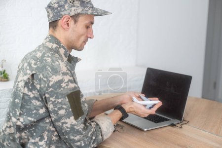 Service technique militaire, Concept de la Force aérienne. Les mains d'un homme en uniforme tenant un avion jouet en argent. Un adulte d'âge moyen en uniforme de camouflage vert. À l'intérieur. Photo de haute qualité