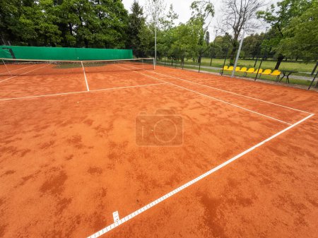 Wet clay tennis court with puddles during the rain. Outdoor tennis season. Spring rain on courts. All practices and match are cancelled. High quality photo
