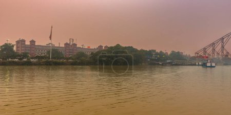 Téléchargez les photos : Kolkata, Inde, 24 janvier 2023 : Howrah Ferry Ghat surplombant la célèbre gare de Howrah et le pont de Howrah. - en image libre de droit