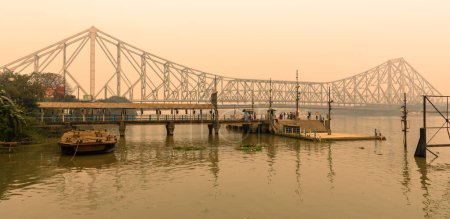 Téléchargez les photos : Kolkata, Inde, 24 janvier 2023 : Howrah Ferry Ghat surplombant le célèbre pont Howrah au moment du coucher du soleil. - en image libre de droit