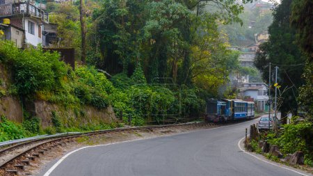 View of  city road of Darjeeling hill station with view of toy train and tourist vehicles. 