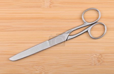 Universal steel scissors on wooden background, close up