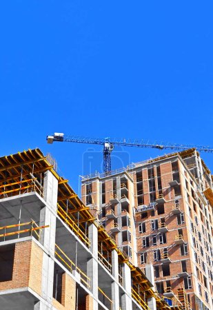 Multistage construction site with crane and blue sky