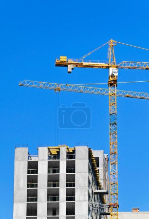 Crane and highrise building construction against blue sky