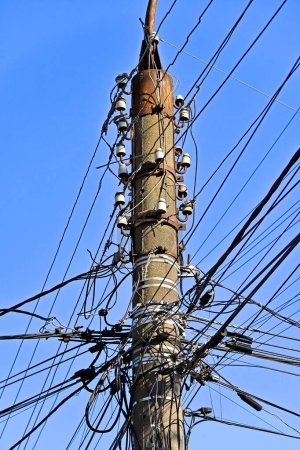 Stromkabel und Isolator am Mast über blauem Himmel