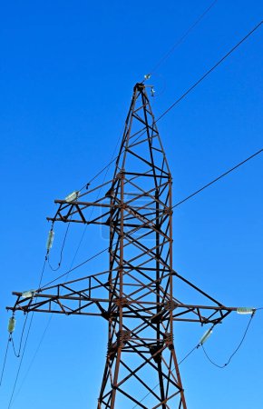 High voltage transmission tower over blue sky background