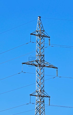 High voltage transmission tower over blue sky background