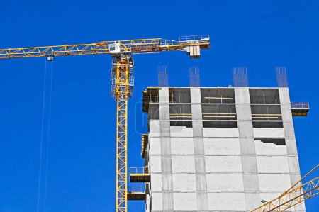 Building crane and construction against blue sky