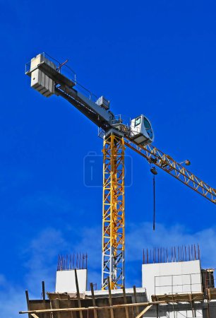 Tower crane and construction against blue sky