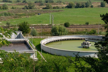 Aerial view of a water treatment plant with circular and rectangular tanks set in a rural landscape surrounded by greenery