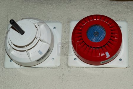 Close-up image of a fire alarm and smoke detector installed on a beige wall. Concept of safety, security, and emergency preparedness