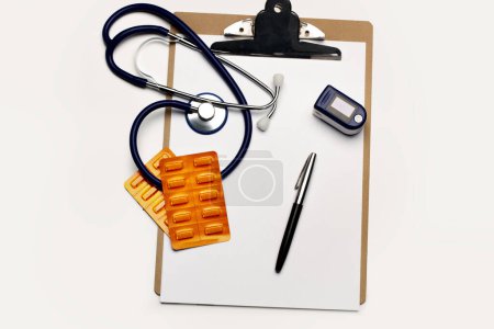 Foto de Pulsómetro de dedo portátil, estetoscopio y ampolla de píldora médica en un portapapeles - Imagen libre de derechos