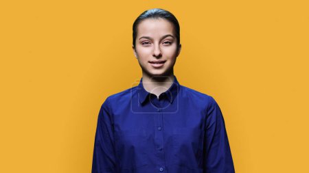 Photo for Portrait of smiling teenage girl 15, 16 years old, positive young female looking at camera on yellow color studio background. Adolescence, high school education, lifestyle, beauty health concept - Royalty Free Image