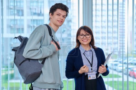 Photo for Portrait of middle aged female teacher and male college student. Woman mentor, tutor and guy looking at camera near window of hallway educational building. Education, learning, language courses, youth - Royalty Free Image