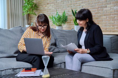 Meeting room, two confident business mature women sitting on couch in office, talking, discussing work. Business, finance, logistics, law, sales concept