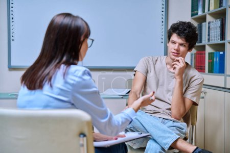 Young guy student 18-20 years old at meeting with psychologist, social worker, college counselor, talking in office. Psychology, psychotherapy, socialization, help support, mental health concept