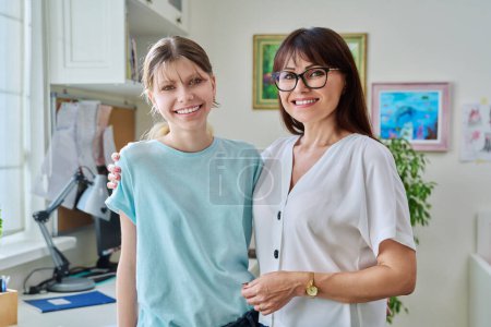 Photo for Portrait of mom and preteen daughter 12, 13 years old smiling hugging looking at camera, together at home. Family, relationship parent mom daughter teenager, adolescence concept - Royalty Free Image