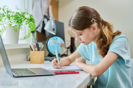Photo for Preteen girl studying at home at her desk using a laptop computer. High school, adolescence, education, technology, knowledge concept - Royalty Free Image