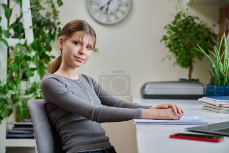 Photo for Portrait of teenage girl sitting at desk at home with laptop computer. Smiling 12, 13 year old young female student looking at camera. High school, adolescence, education, lifestyle concept - Royalty Free Image