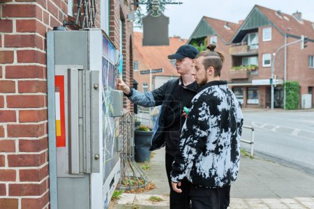 Téléchargez les photos : Distributeur automatique de cigarettes en plein air dans la rue de la ville, les jeunes hommes achètent des cigarettes. - en image libre de droit
